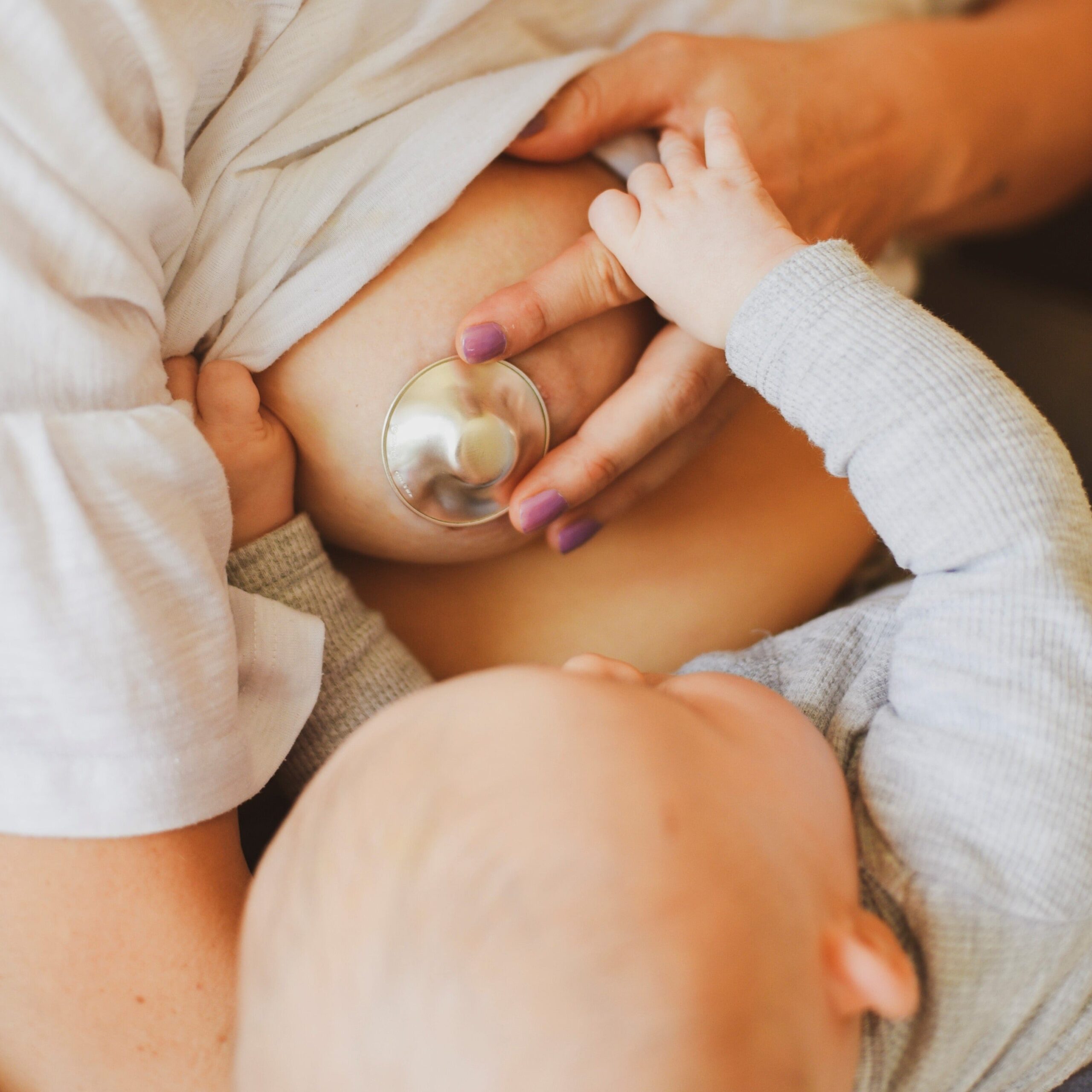 Madre che allatta il proprio neonato applicando la coppetta in argento Silverette al seno