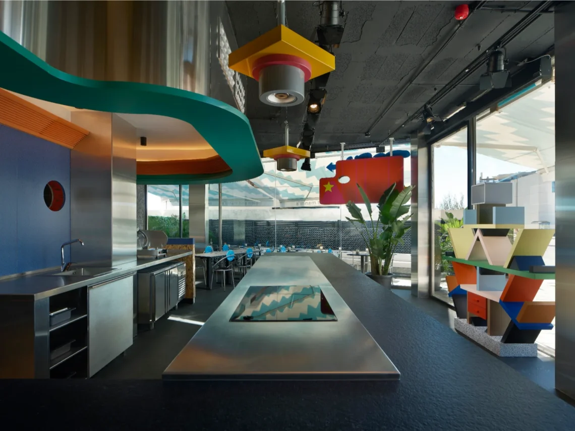 Interni del ristorante Seth and Manni's a Ibiza con la celebre libreria scultura Carlton di Ettore Sottsass, bancone in acciaio e lampade Memphis