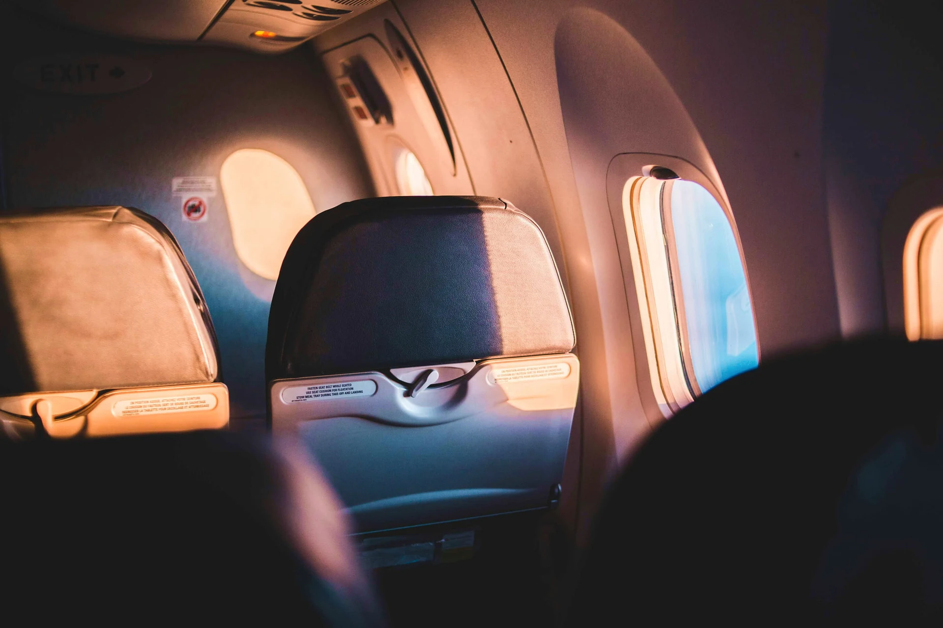 Finestrini di un aereo passeggeri illuminati dalla luce dorata del tramonto durante il volo